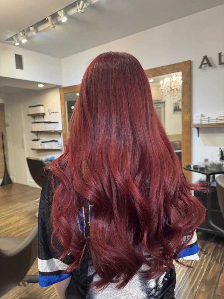 Long red hair with loose waves, seen from behind in the salon