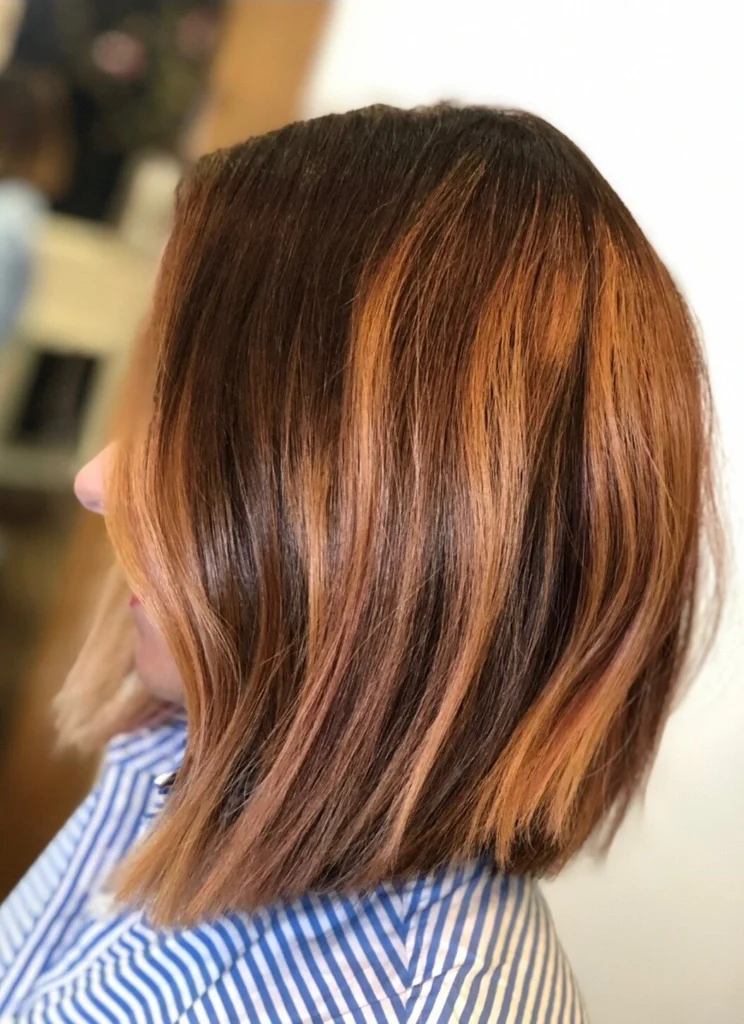 Sleek, glossy brunette bob with copper pieces, seen in profile