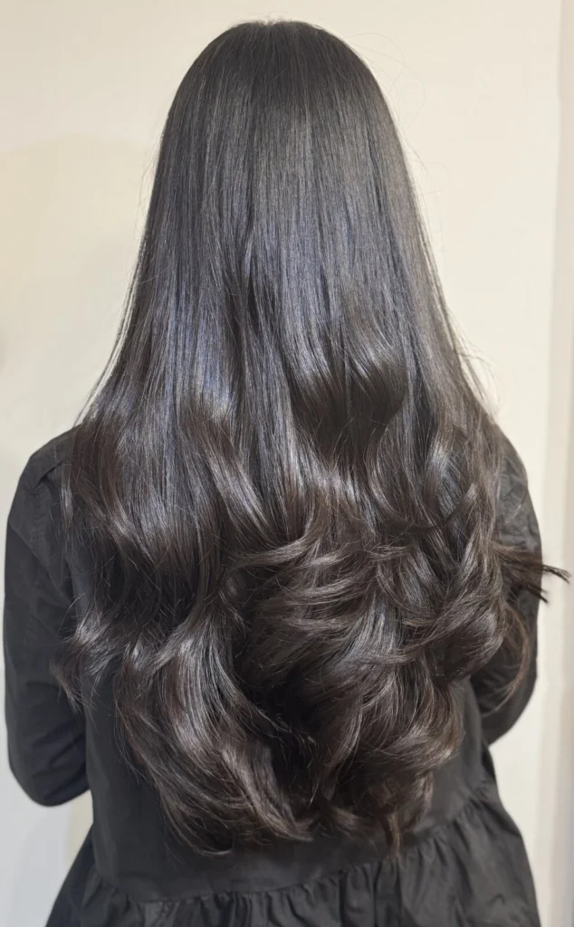 Long, glossy dark brown hair in big curls, seen from behind