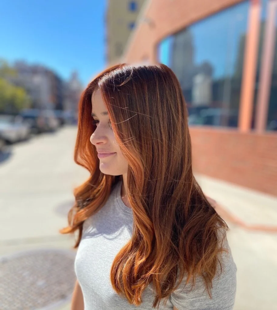Long copper hair with soft layers, photographed on the street outside